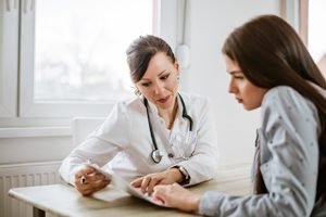 Frauenaerztin erklärt Patienten etwas anhand von Unterlagen