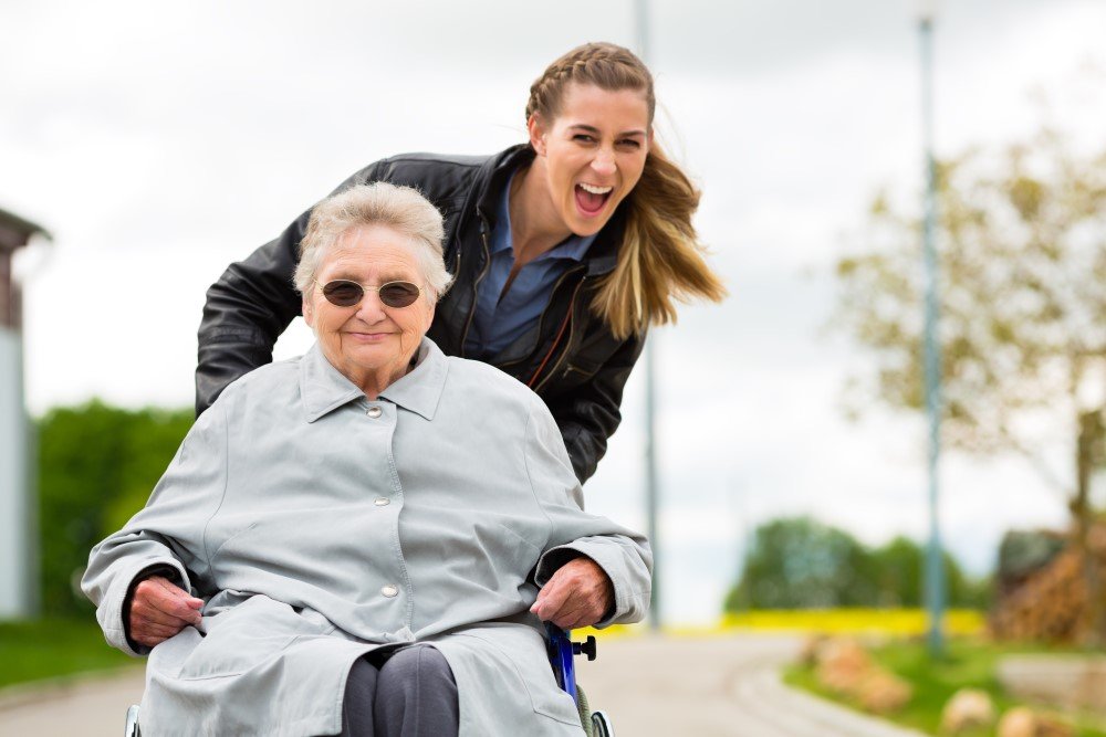 Frau mit Großmutter im Rollstuhl