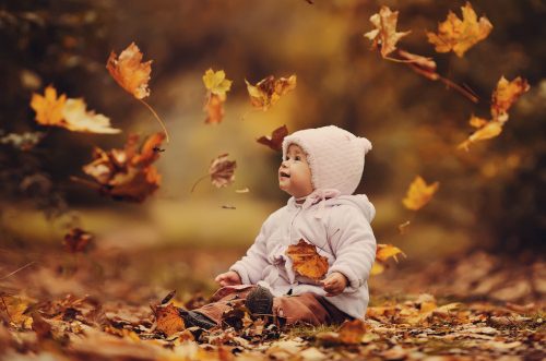 Kind in Herbstblättern