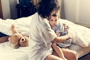 Mama neben Kind im Bett nach Alptraum