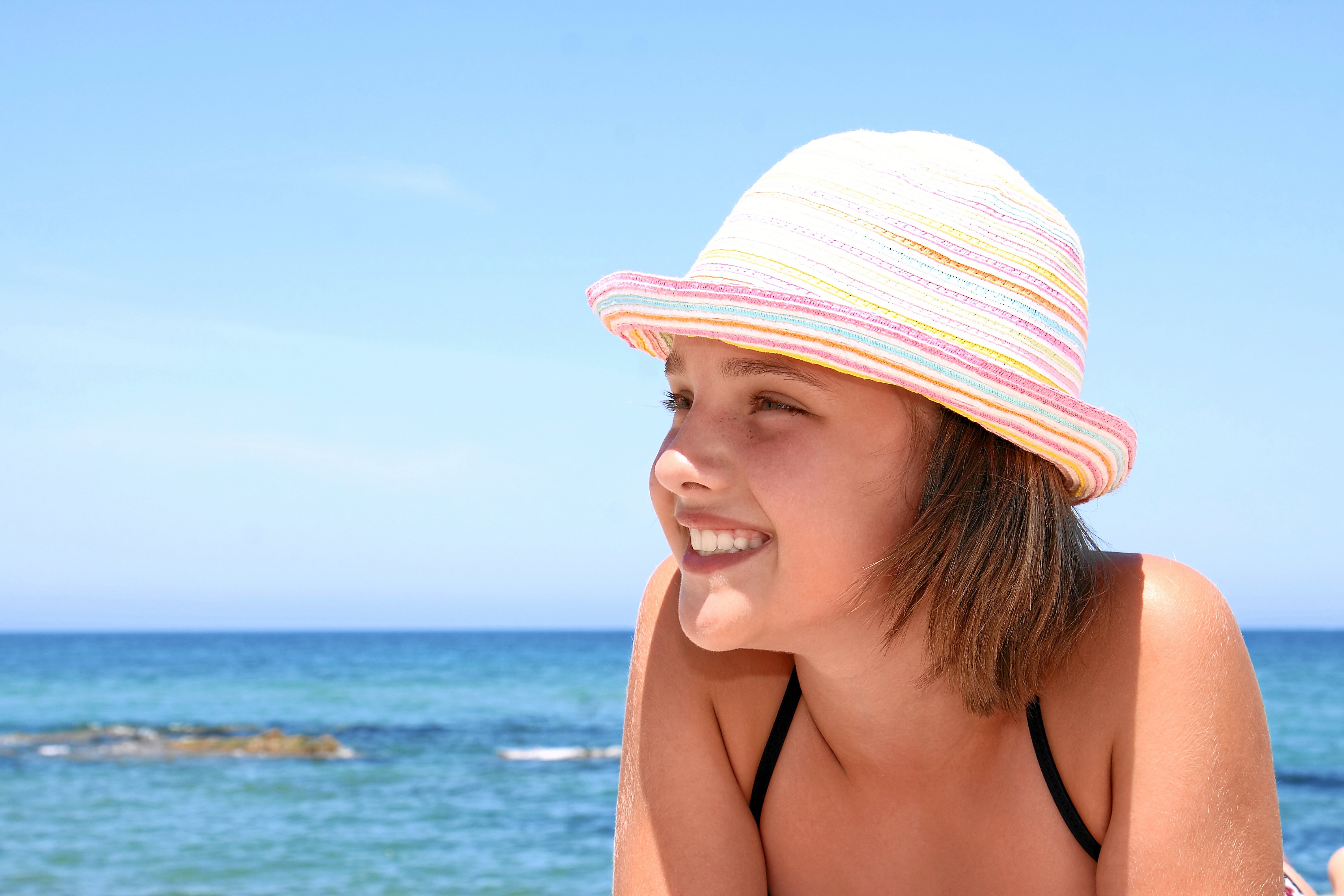 Sonnenstich bei Kindern: Symptome, Dauer und Tipps zur Behandlung mädchen am strand mit mütze.