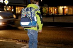 Kind mit reflektierenden Stellen am Ranzen im Dunkeln
