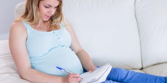 schwangere Frau schreibt auf einem Block