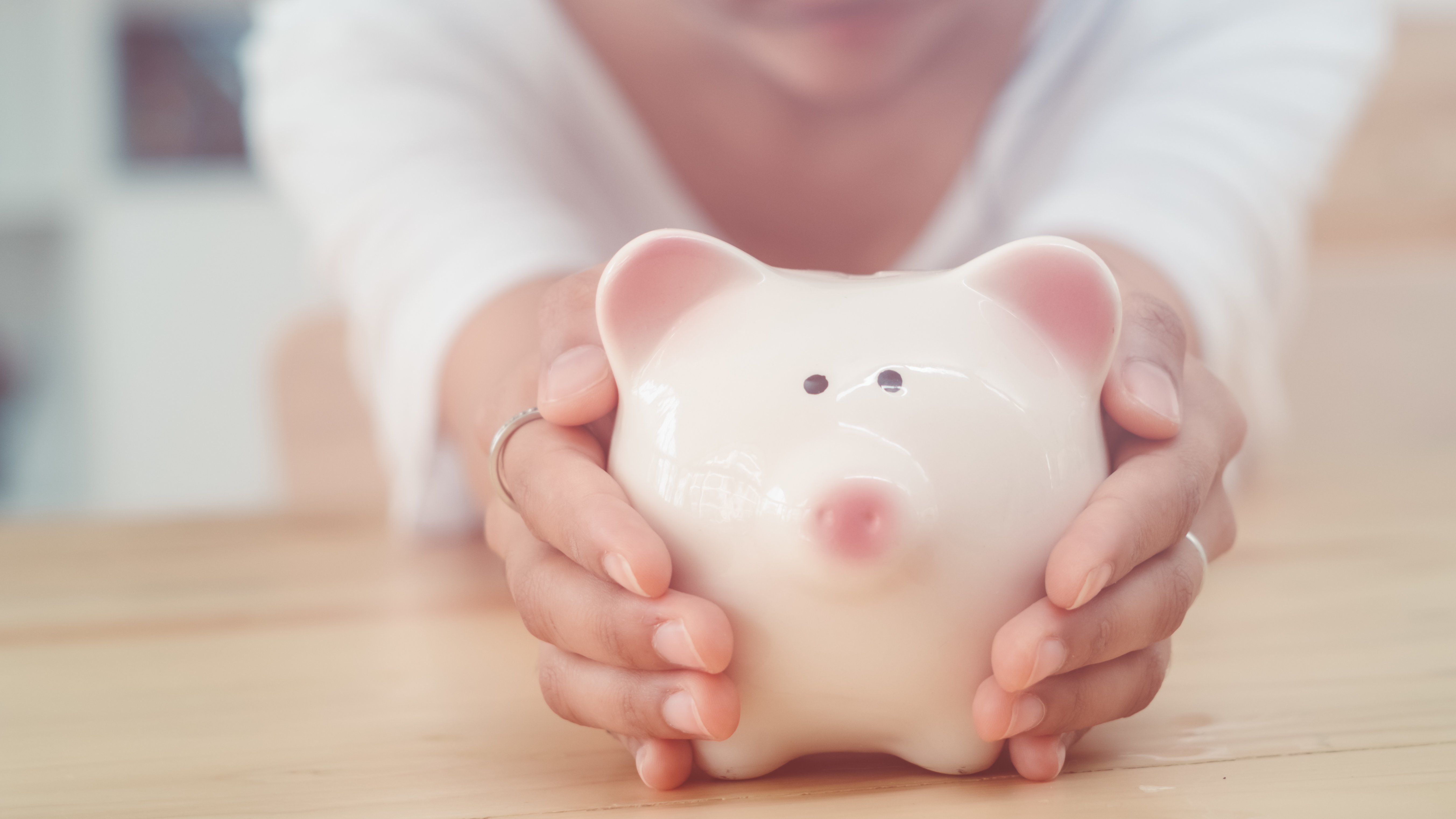 Elterngeldbescheid: Das müssen Sie bei der Post von der Elterngeldstelle beachten Hände halten Sparschwein in die Kamera