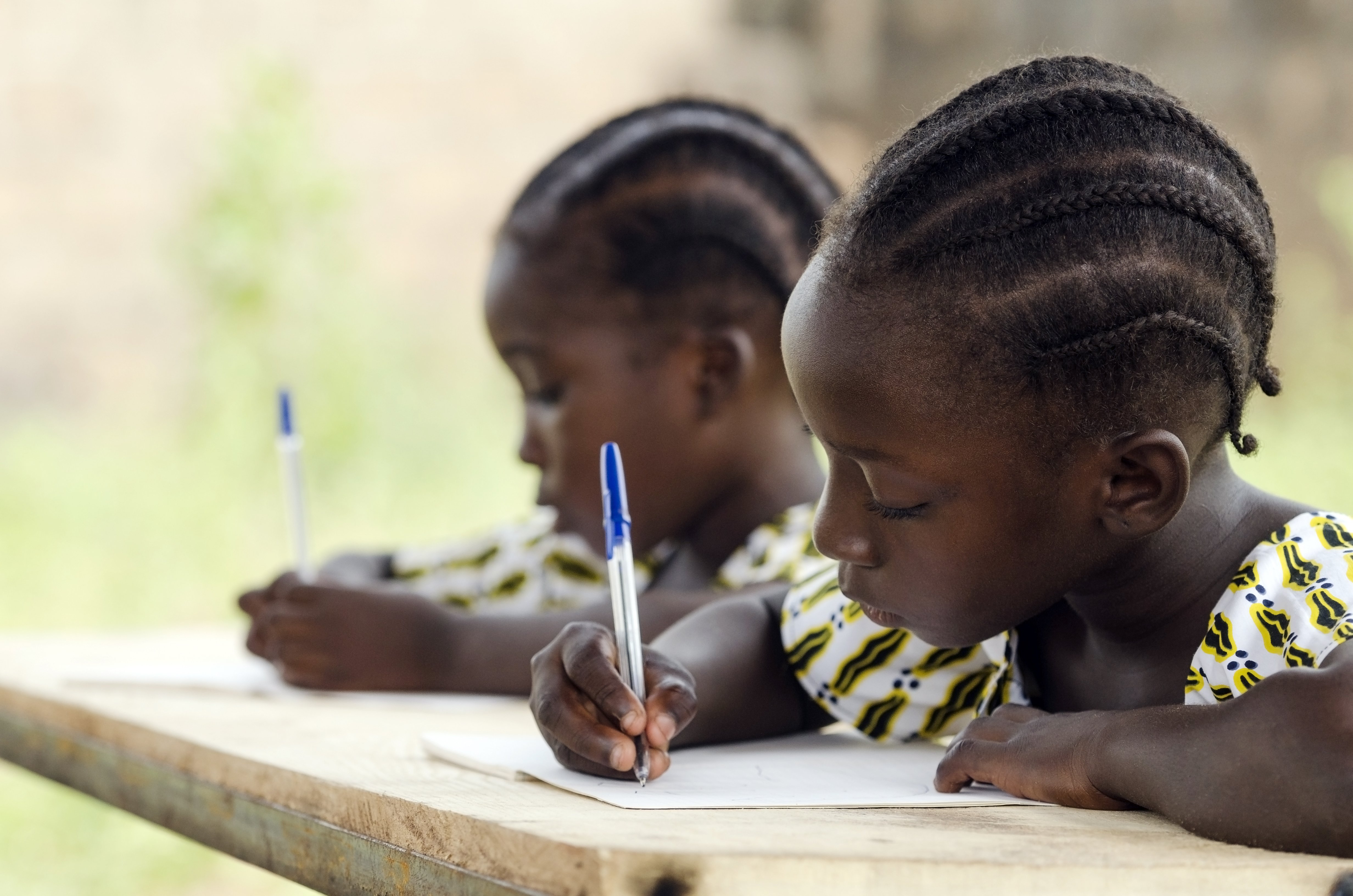 zwei afrikanische Kinder lernen an einem holztisch