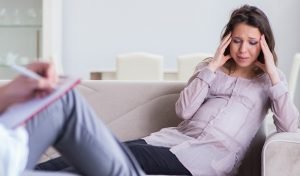 schwangere frau sitzt verzweifelt bei einem psychologen