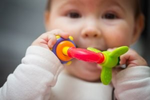 Kind nimmt Babyspielzeug in den Mund