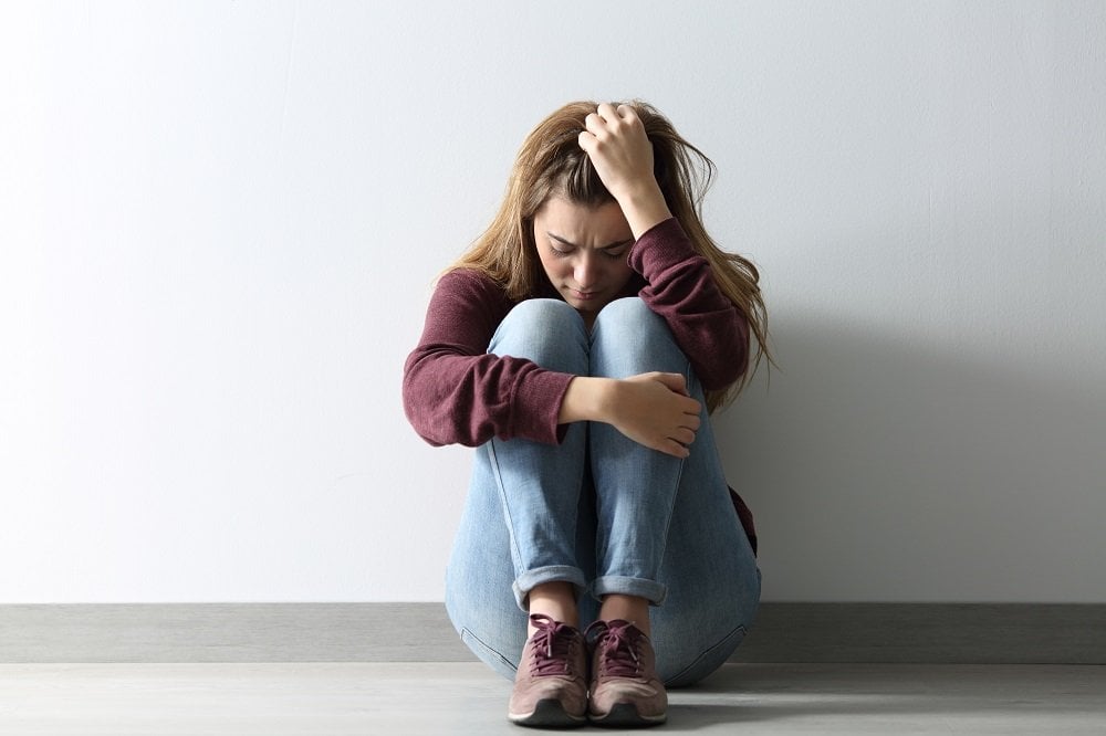 Frau mit Verlustangst sitzt allein auf dem Boden