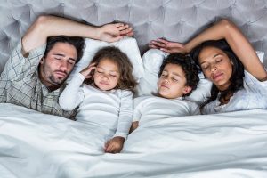 glückliche Familie schläft zusammen im Bett