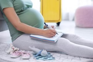 schwangere frau macht sich eine liste fuer besorgungen
