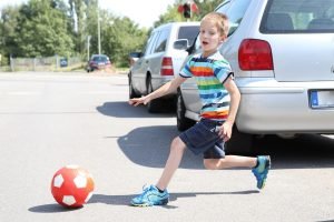 Kind rennt nach Ball auf die Straße