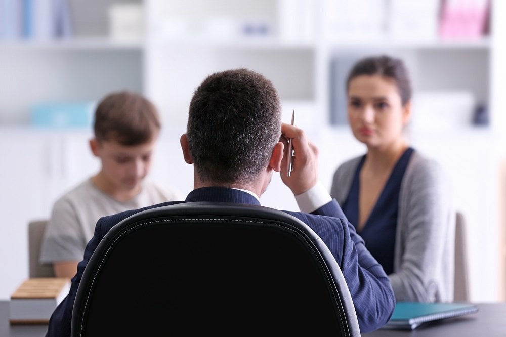 mutter mit ihrem jungen in einem gespraech mit der schulleitung