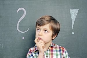 Kind steht vor einer Tafel mit einem Ausrufezeichen sowie einem Fragezeichen