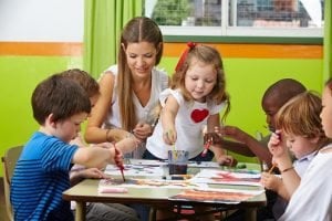 Kinder malen zusammen mit Erzieherin