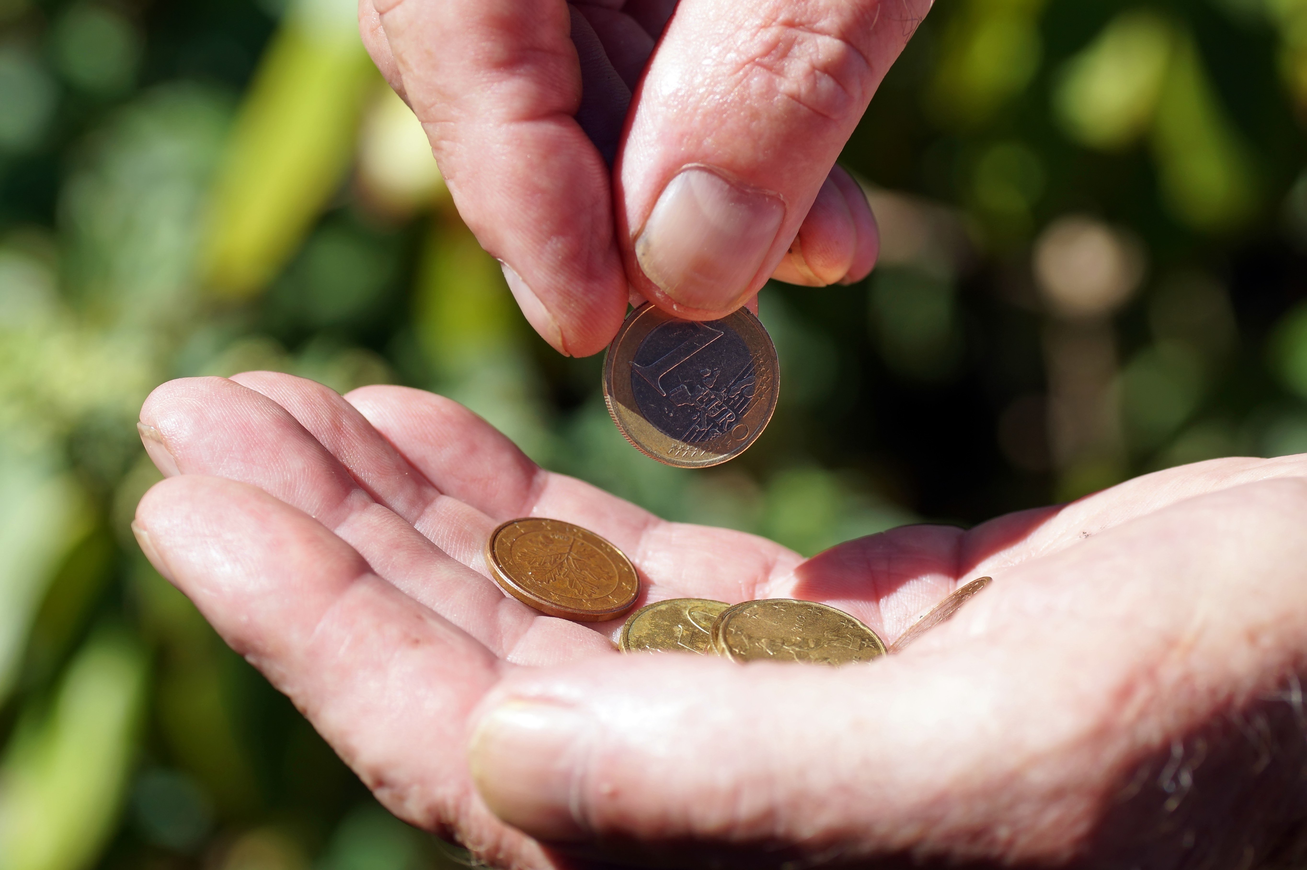 Elterngeld für Geringverdiener: Sie erhalten bis zu 100% Ihres Nettogehalts hände mit Geldmünzen