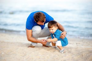 Mann spielt mit einem Kind am Strand