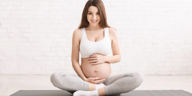 schwangere frau auf yoga matte