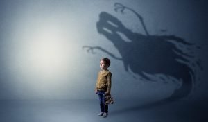 Kind steht vor einer Wand mit einem schaurigen Schatten