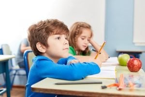 ein grundschueler sitzt konzentriert am tisch