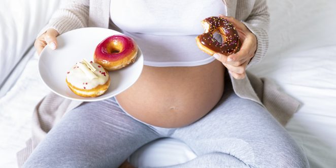 Schwangere Frau isst Donuts