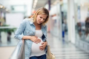Schwangere Frau mit Wehen im Einkaufszentrum
