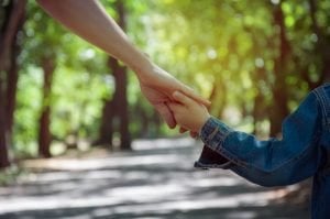kind haelt die hand eines erwachsenen fest