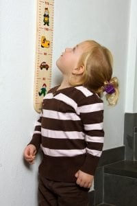 kleines maedchen vor einer messlatte